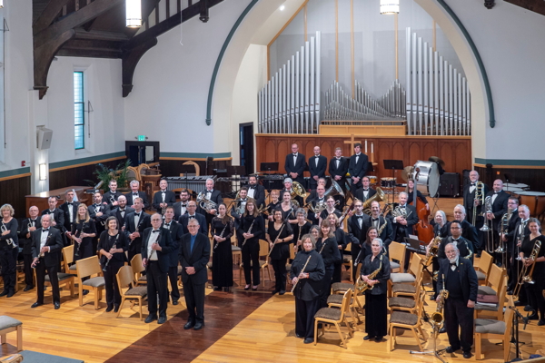 Boulder Concert Band standing in ensemble in First Congregational Church, with conductor at front, facing the camera