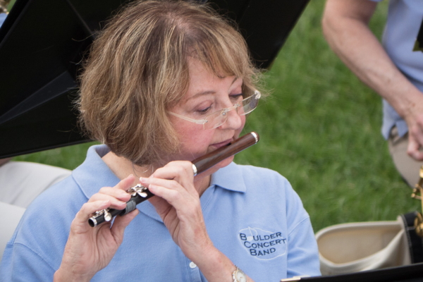woman in light blue polo shirt playing flute outdoors