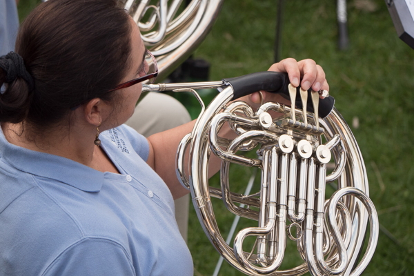 woman in light blue polo shirt playing french horn