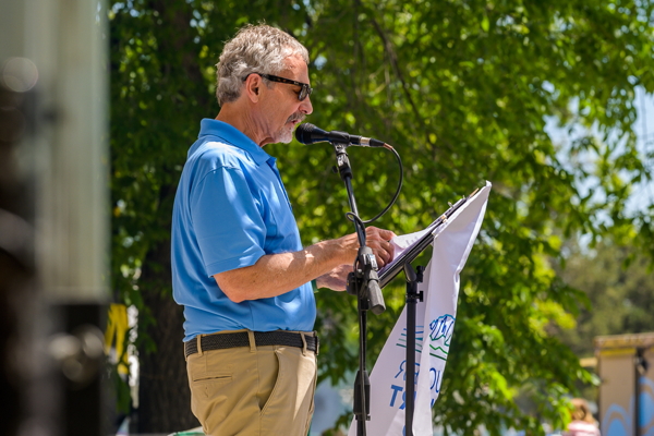 man in blue shirt reading before a microphone