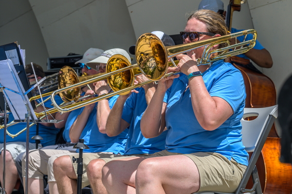 four seated trombone players in blue shirts