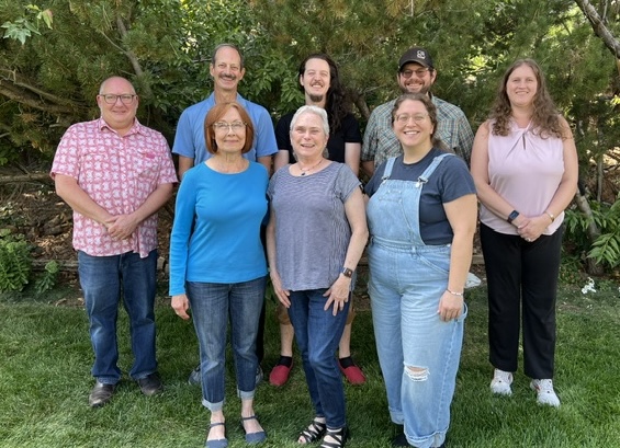 eight smiling people standing in two rows