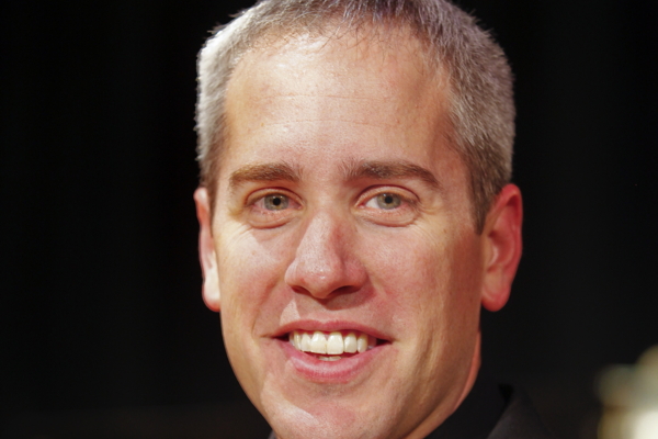 man in black suit, black shirt and red tie