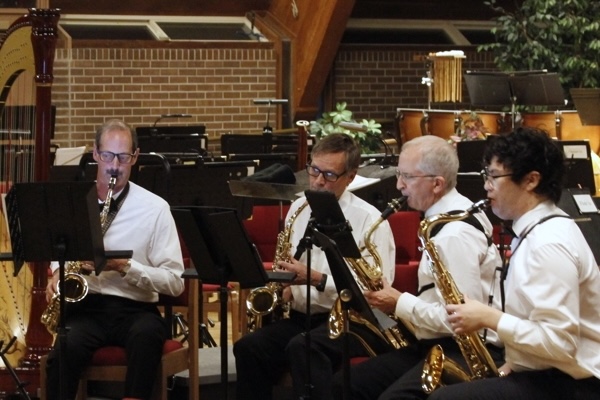 four men in white shirts, seated and playing saxophones