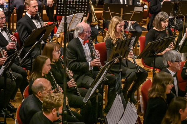 a group of people dressed in black concert attire, playing clarinets