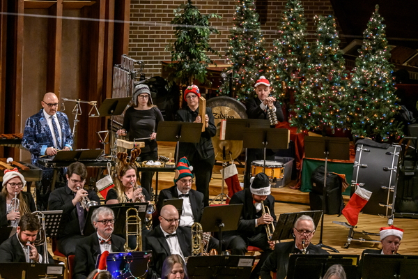 small segment of the band, with five white-lit Christmas trees in the background