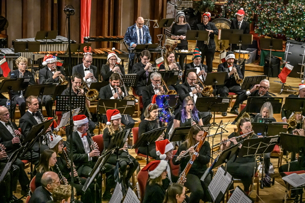 band playing 'Sleigh Ride' in red and white Santa hats. Some have Christmas lights decorating their music stands