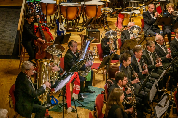 people seated, playing string bass, tubas, euphoniums, and clarinets