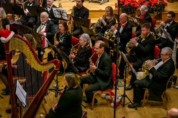 people in formal black attire, playing harp, saxophones and french horns