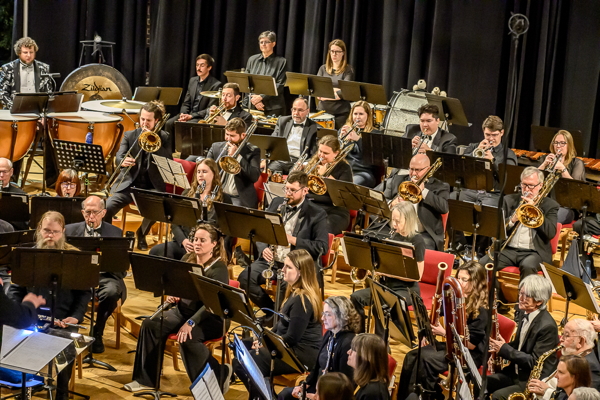group of people dressed in concert black, seated and playing various wind instruments