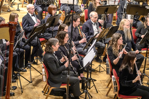 group of people dressed in black and playing clarinets