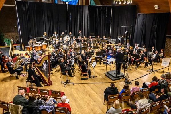 concert band dressed in black, facing an audience and their director.